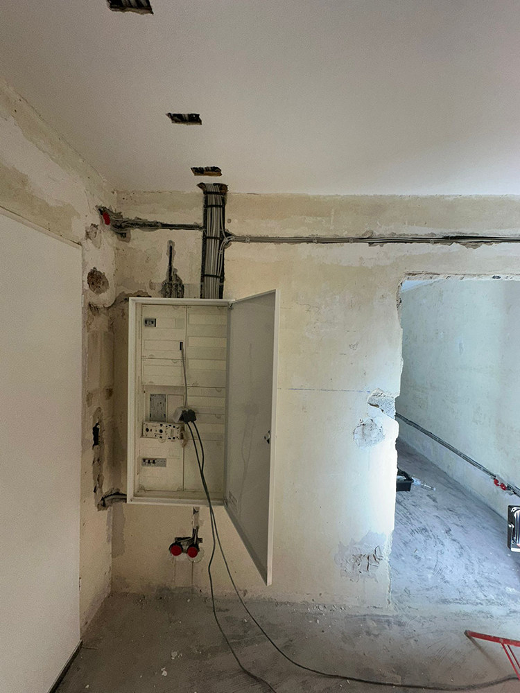 Offener weißer Elektroverteilerkasten in Raum mit abgeblätterten Wänden