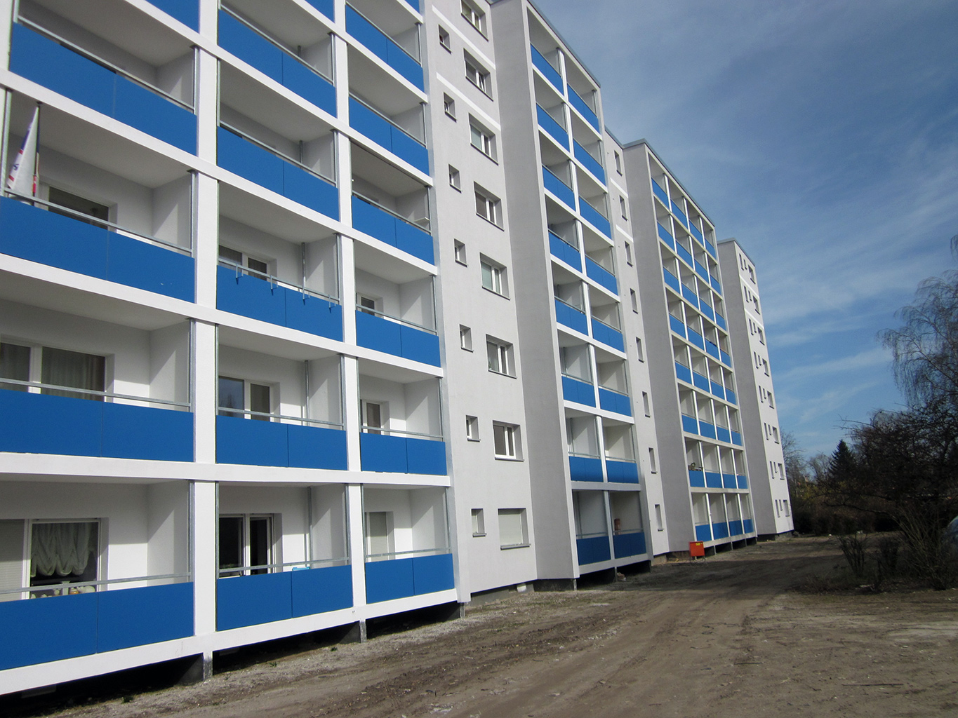 Modernes hohes Wohngebäude in Weiß-Grau mit blauen Balkonen