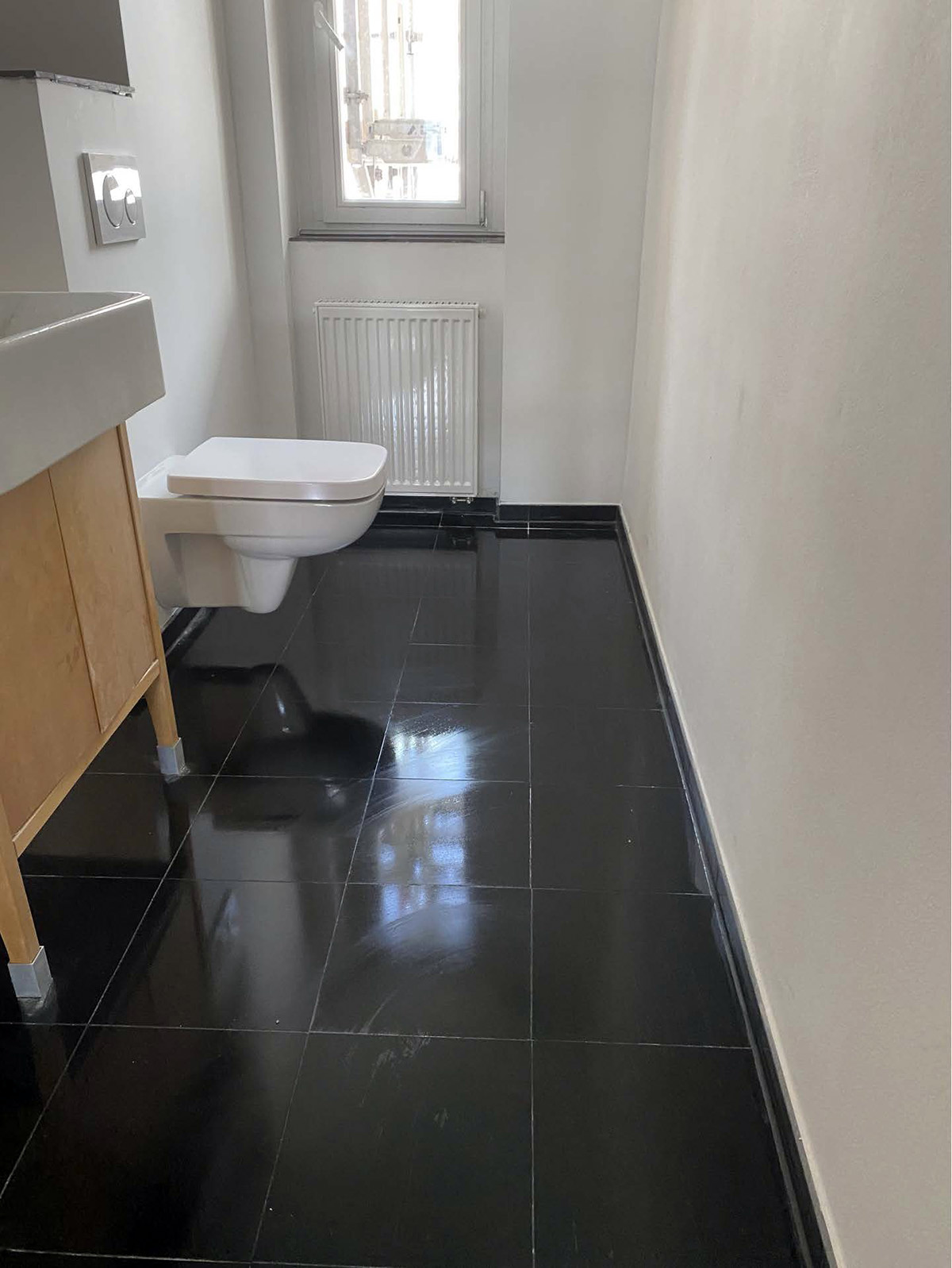 Fertige moderne Badezimmerecke mit weißem WC und schwarzen Bodenfliesen